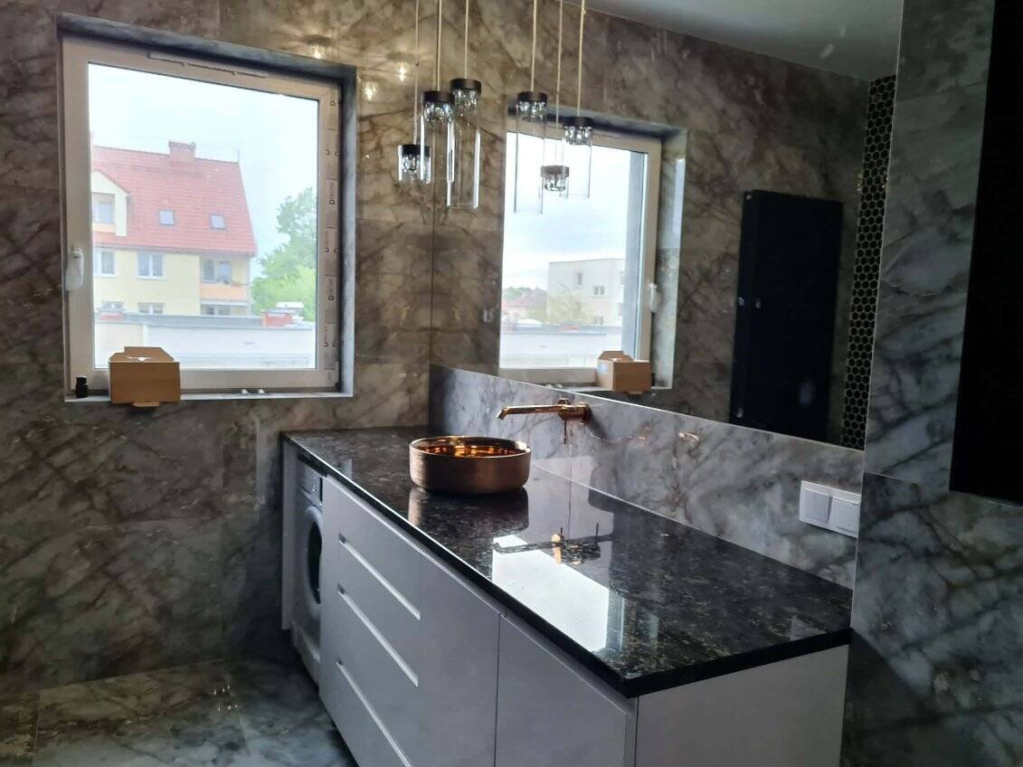 Nowoczesna łazienka z marmurowymi ścianami i eleganckim blatem.